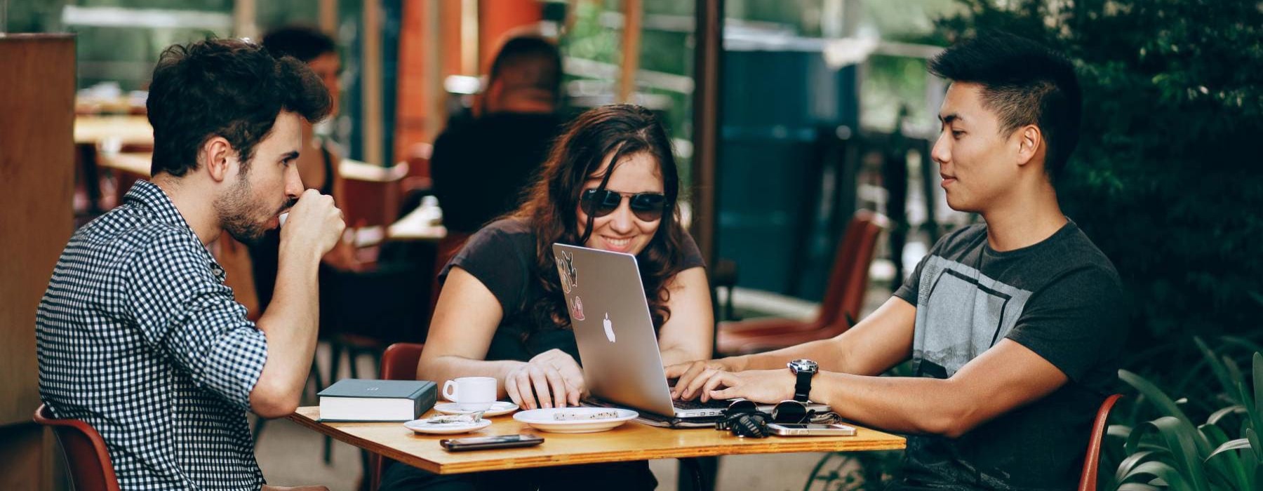 a group of people sitting around a table with a laptop